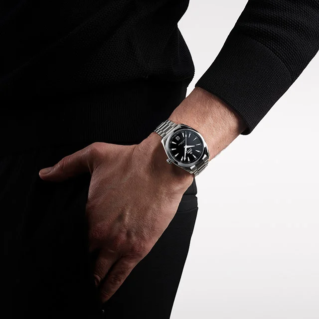 A person wearing a wrist watch putting their hand in their pocket.