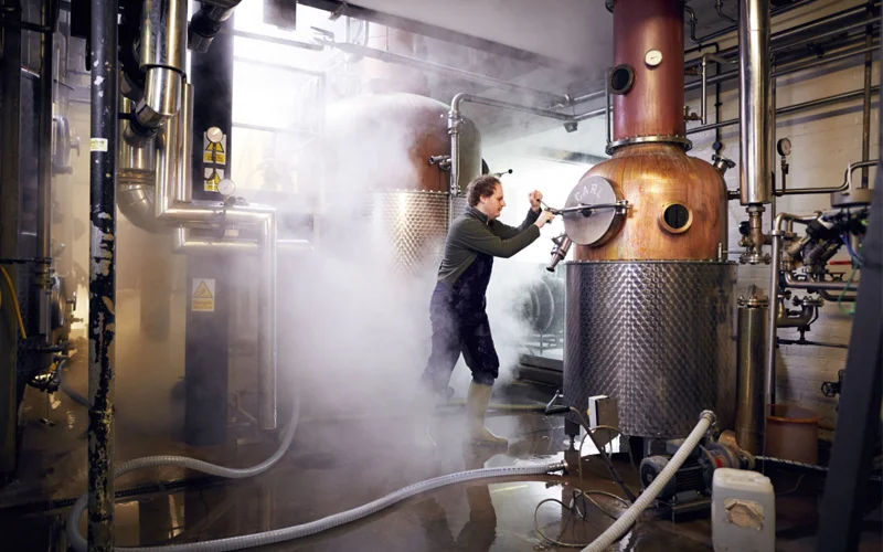 A man works a machine to distill gin.
