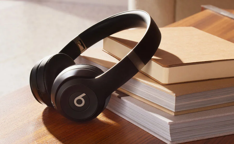 Beats Solo 4 headphones leaning against a pile of books