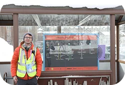 A volunteer in front of a bus station Festival map.