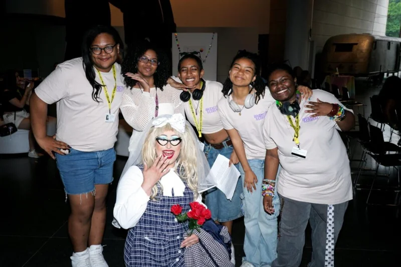 A group of teens posing with a drag artist