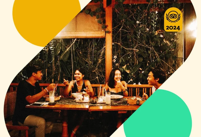 Image Description: A group of friends dining in an open-air restaurant with a lush vine wall
