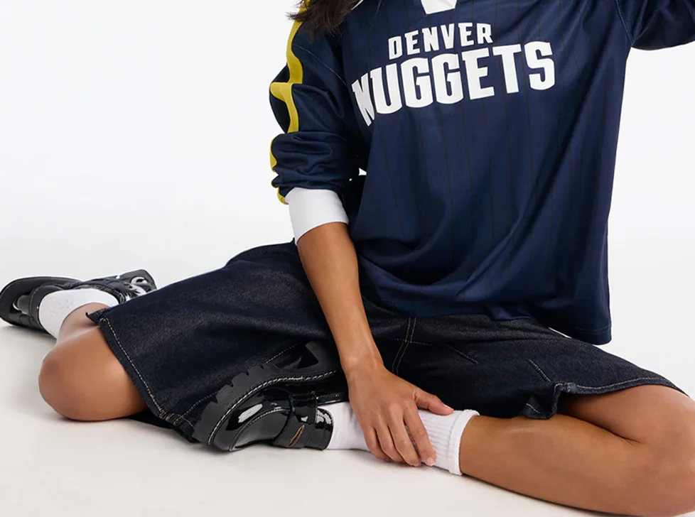 Navy blue Denver Nuggets NBA jersey with yellow stripes, dark denim shorts, white socks, and black patent leather loafers, highlighting current casual team wear.