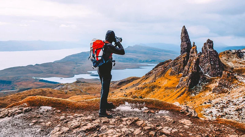 Image description: Tourist photographing Old Man of Storr, on Isle of Skye.