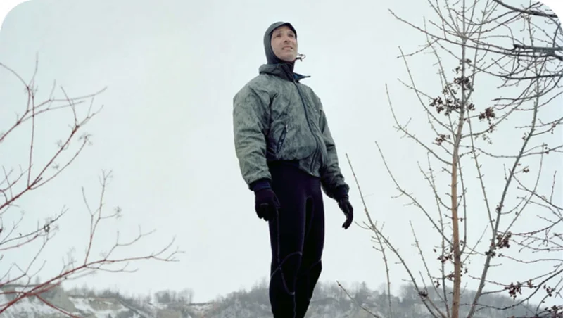 A person standing outside in a wetsuit with a jacket layered over it.