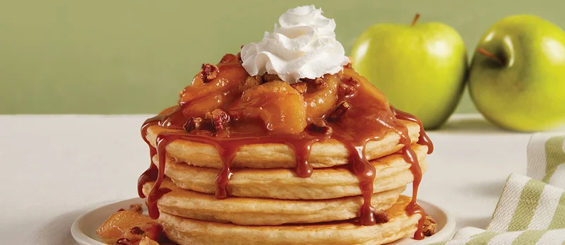 Image showing full stack of Cinnamon Apple Pecan pancakes topped with whipped cream