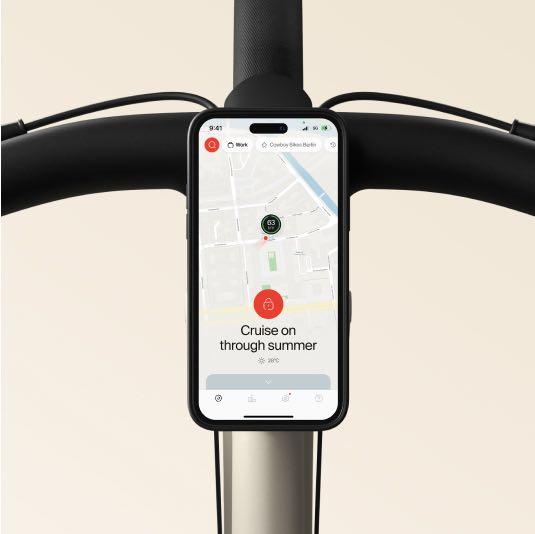 A photographic render. A smartphone displaying the Cowboy app is mounted to the bike's handlebars