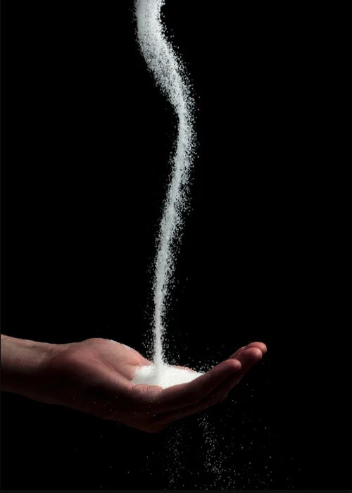 A stream of salt being poured into an open palm.