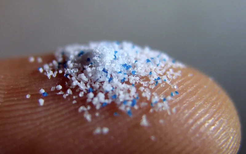 A close up of tiny plastic particles on a human finger.