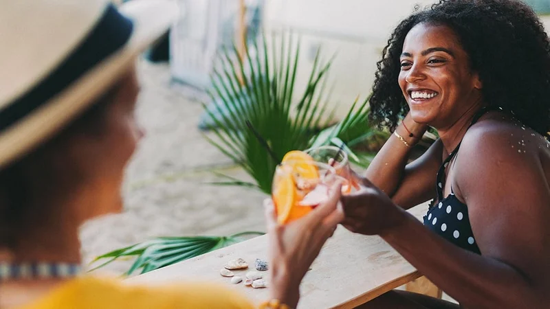 Image Description: Two friends drinking cocktails at outdoor bar