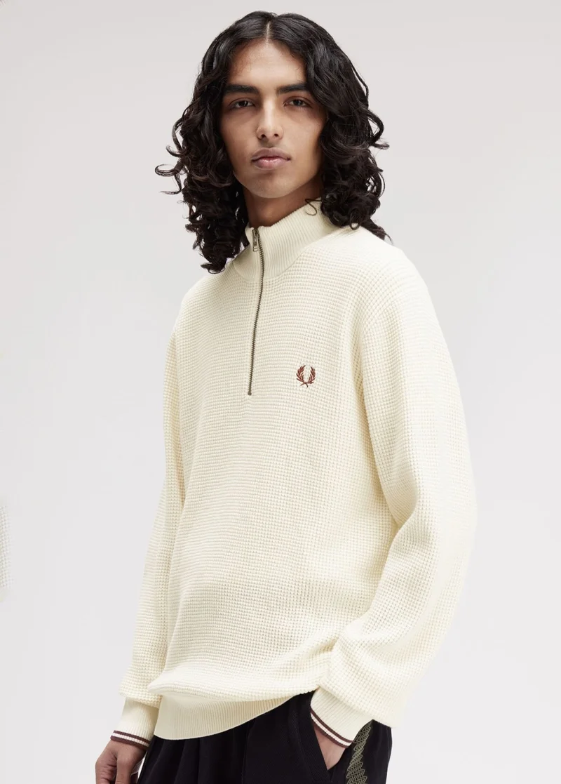 A male model wearing a Fred Perry Waffle Stitch Half-Zip Jumper in Ecru