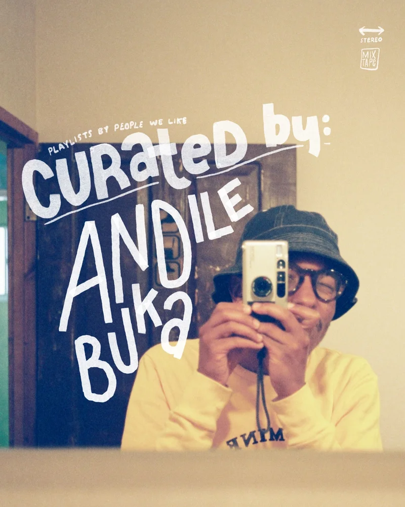 Person in a yellow sweater and bucket hat takes a mirror selfie with a camera. Text reads "Curated by: Andile Buka."