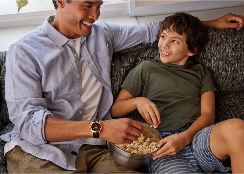 Father and son having popcorn on a sofa