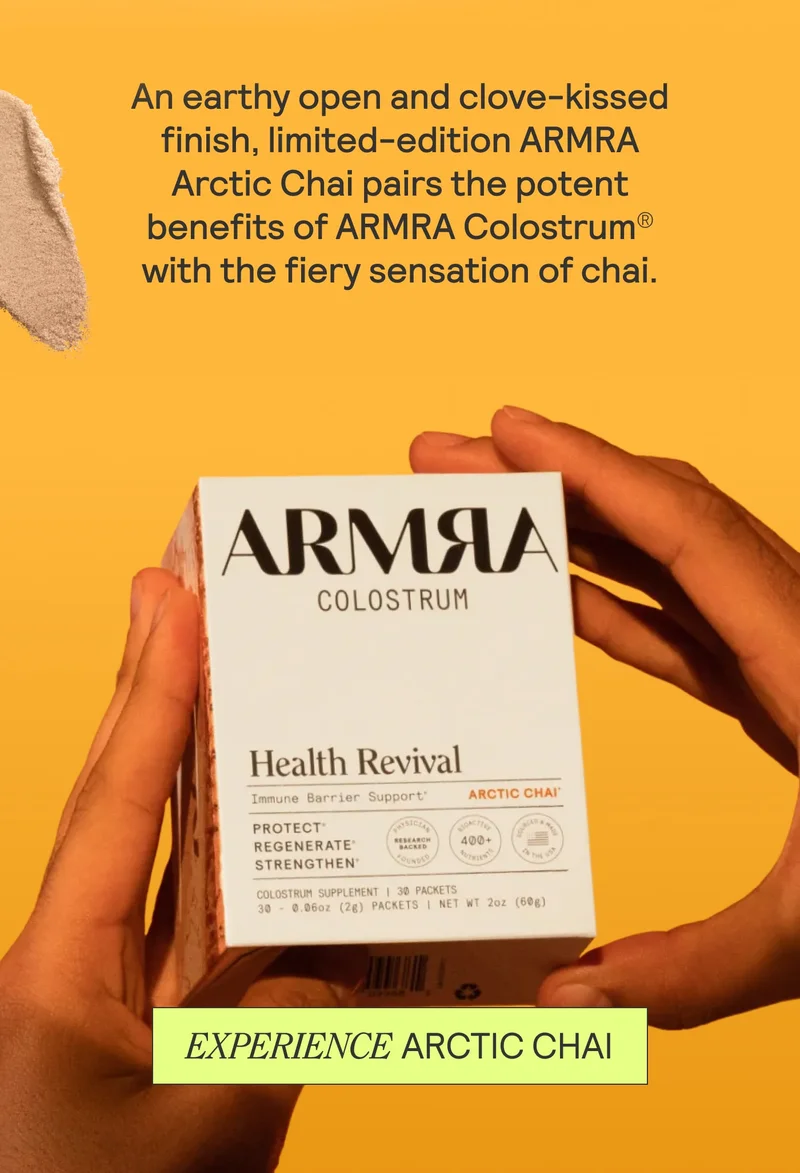 Hand holding ARMRA Arctic Chai box against an orange background with call-to-action button.