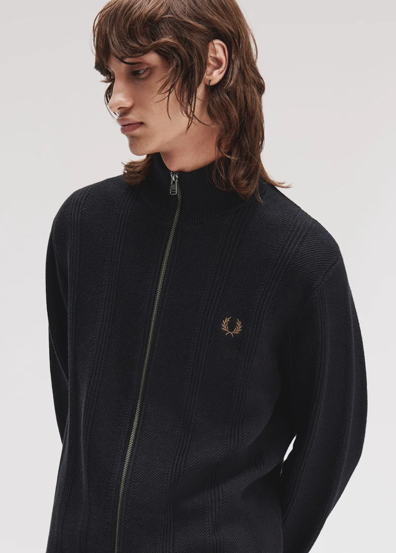 White male model with wolf cut hair looks sideways while wearing a full zip high neck navy long sleeved sweatshirt