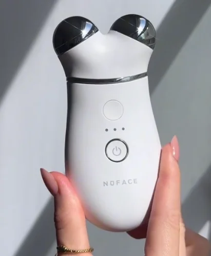 Hand holding TRINITY+ device that showcases the boost button available to send 25% more microcurrent power