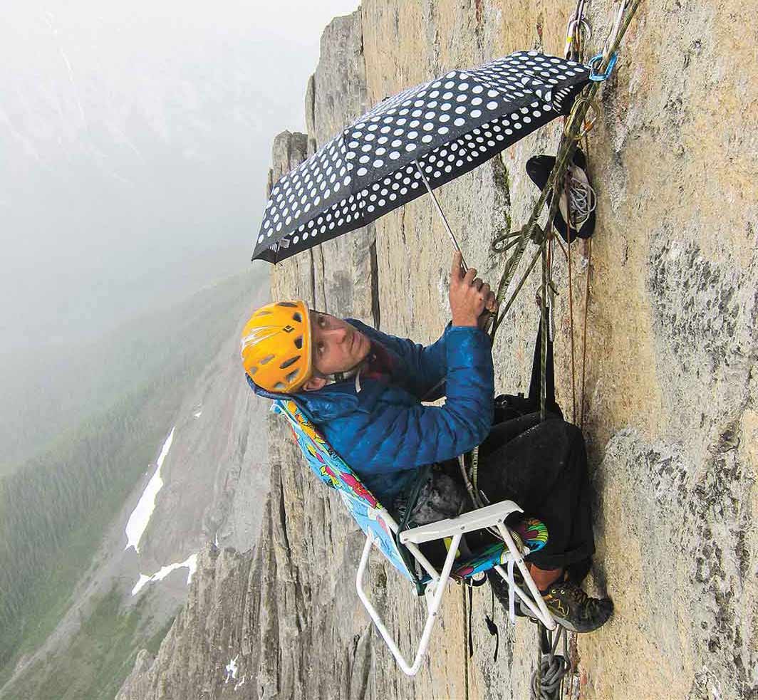 A person sitting in a folding chair tied to a rope on a mountain.