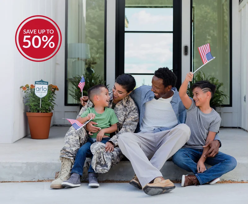 Get up to 50% off. Various Arlo security products near the front door of a home where a veteran sits with her family.
