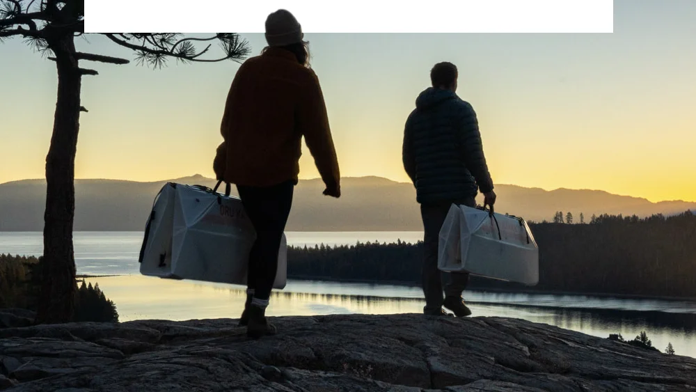 two people carrying their oru foldable kayak