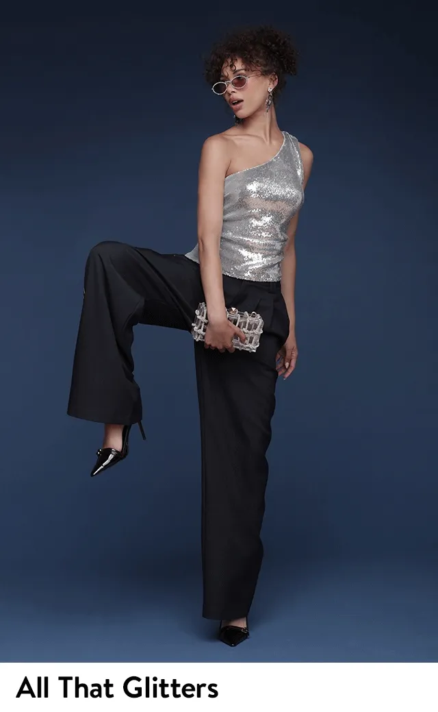 A woman wearing a sparkly one-shoulder top with pants and heels.