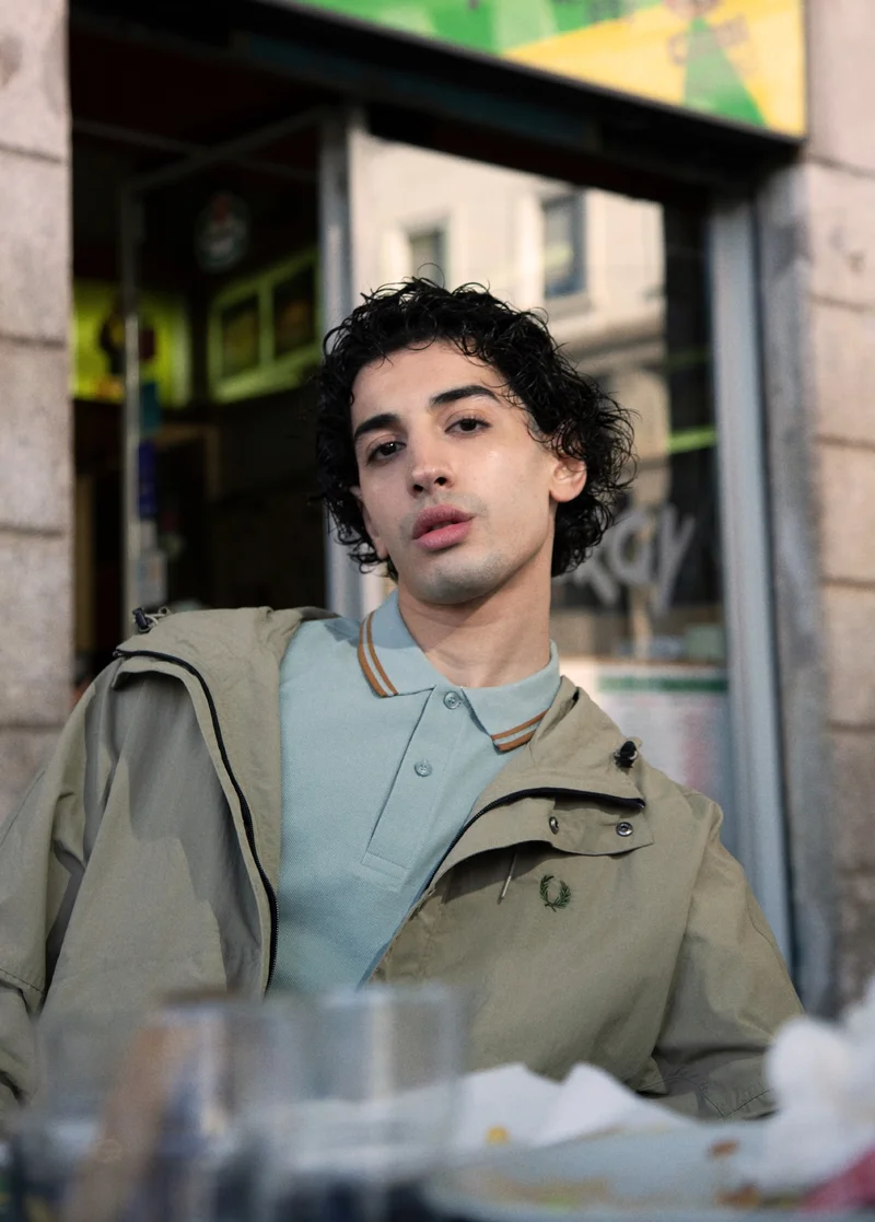 Male model wearing a light blue fred perry twin tipped short sleeved polo shirt and jacket