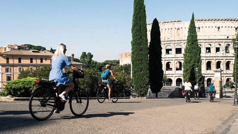 Friends riding bikes past the Colosseum, in Rome