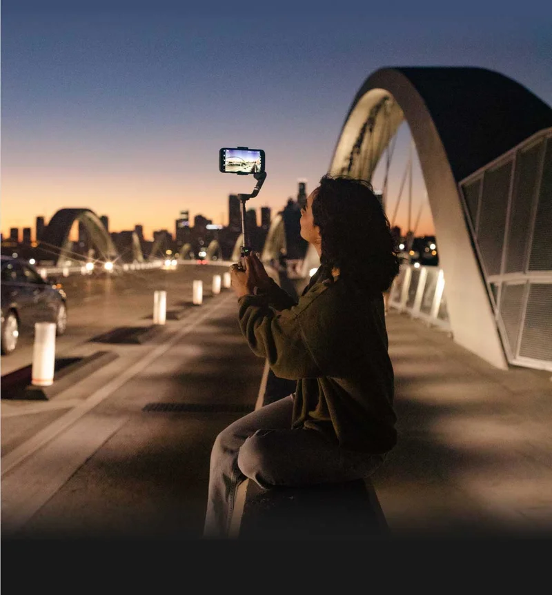 Image of a woman holding a gimbal and filming with a phone
