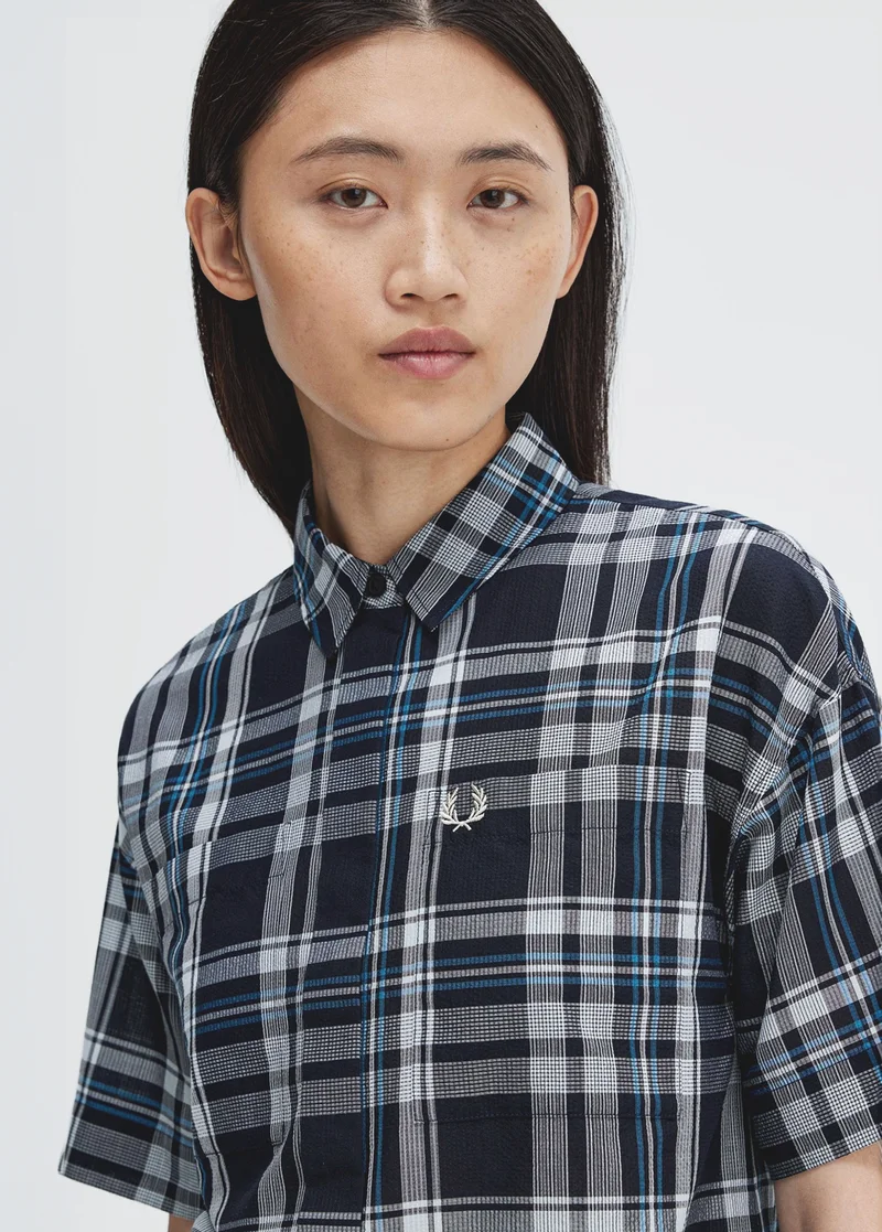 Woman wearing a blue, short sleeved, tartan shirt