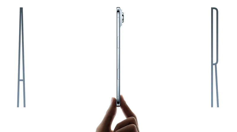 The word Air, spelled in thin chrome-colored letters. The I in Air is a side view of an iPhone Air device in Cloud White being held upright between the thumb and pointer finger of a hand. The side view of the iPhone Air shows a button and part of a camera peeking out from the top right.