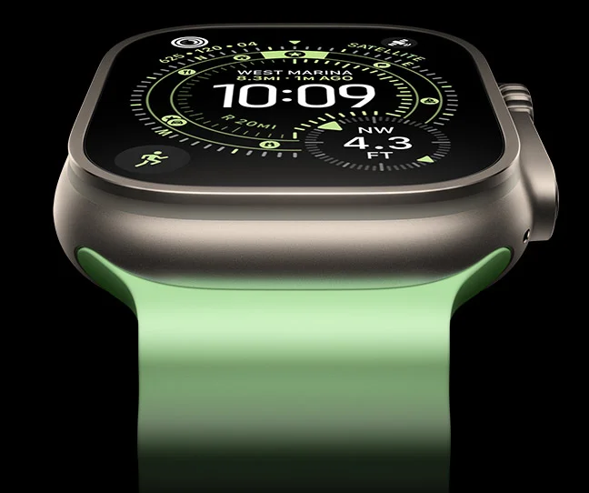 A close-up of a Natural Titanium Apple Watch Ultra 3 on a black background. The display shows the time and other dynamic info.