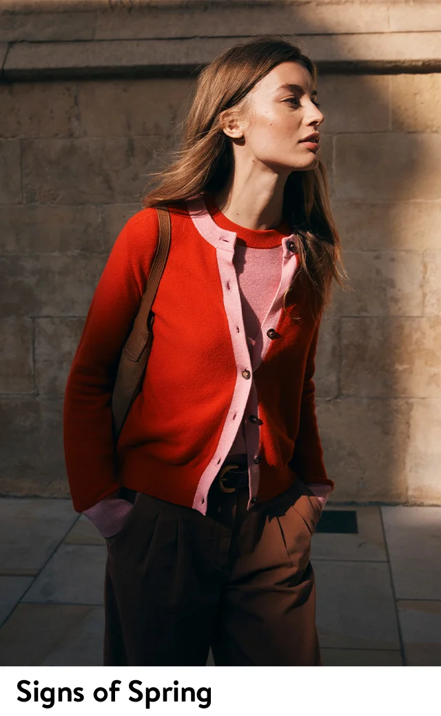 A woman wearing red cardigan with pink trim over a coordinating pink knit top with red trim.