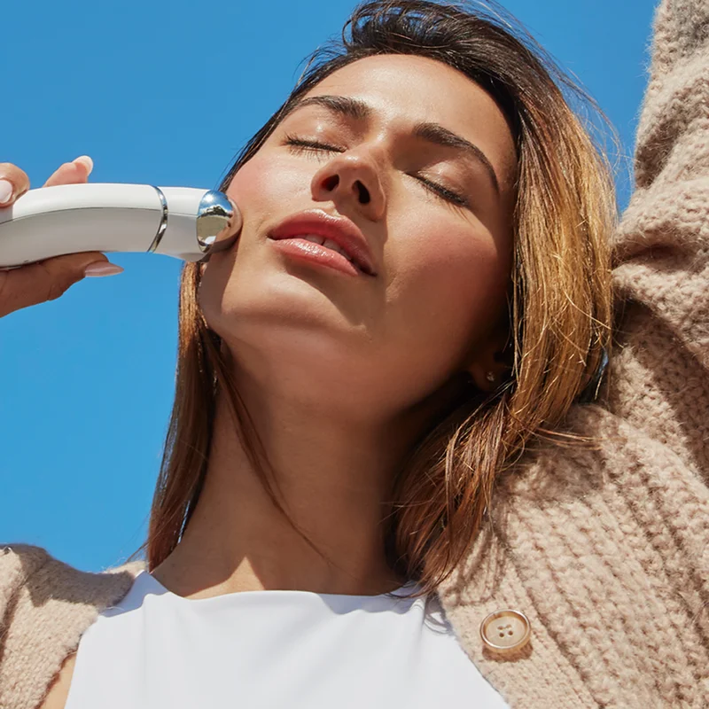 Woman holding TRINITY+ underneath cheek contour