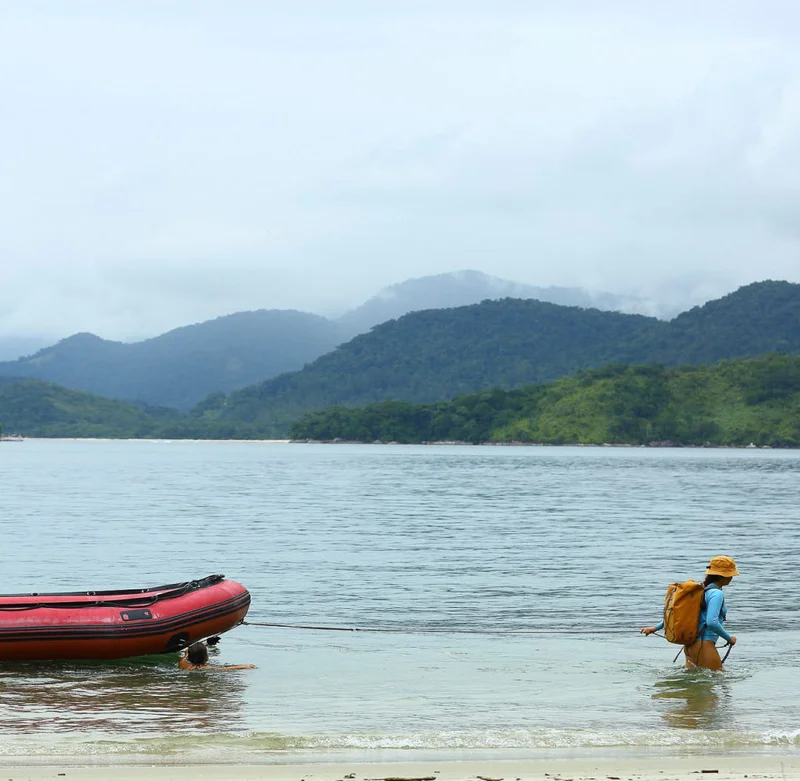 Patagonia. A person walking through water dragging a boat.