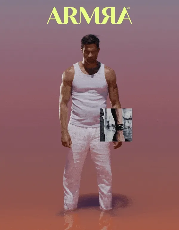ARMRA logo above a fit man standing confidently in a minimal, pink-toned environment, wearing a white tank and pants.