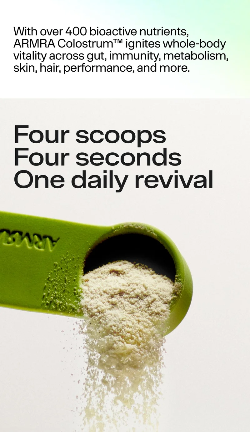 Green measuring scoop pouring fine colostrum powder against a clean, light background.
