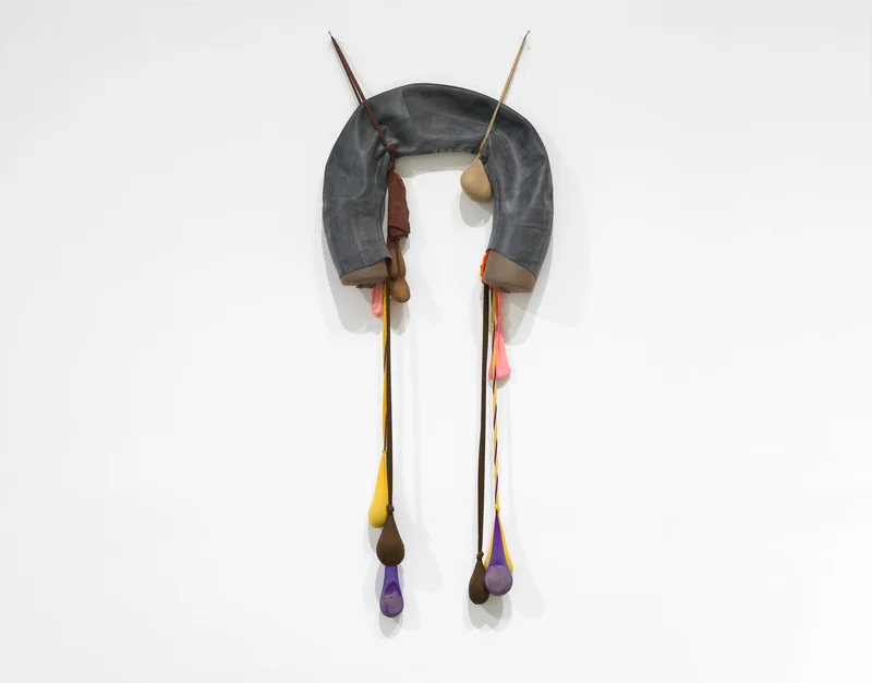 Wall installation comprising a gray rubber tube and colorful pantyhose