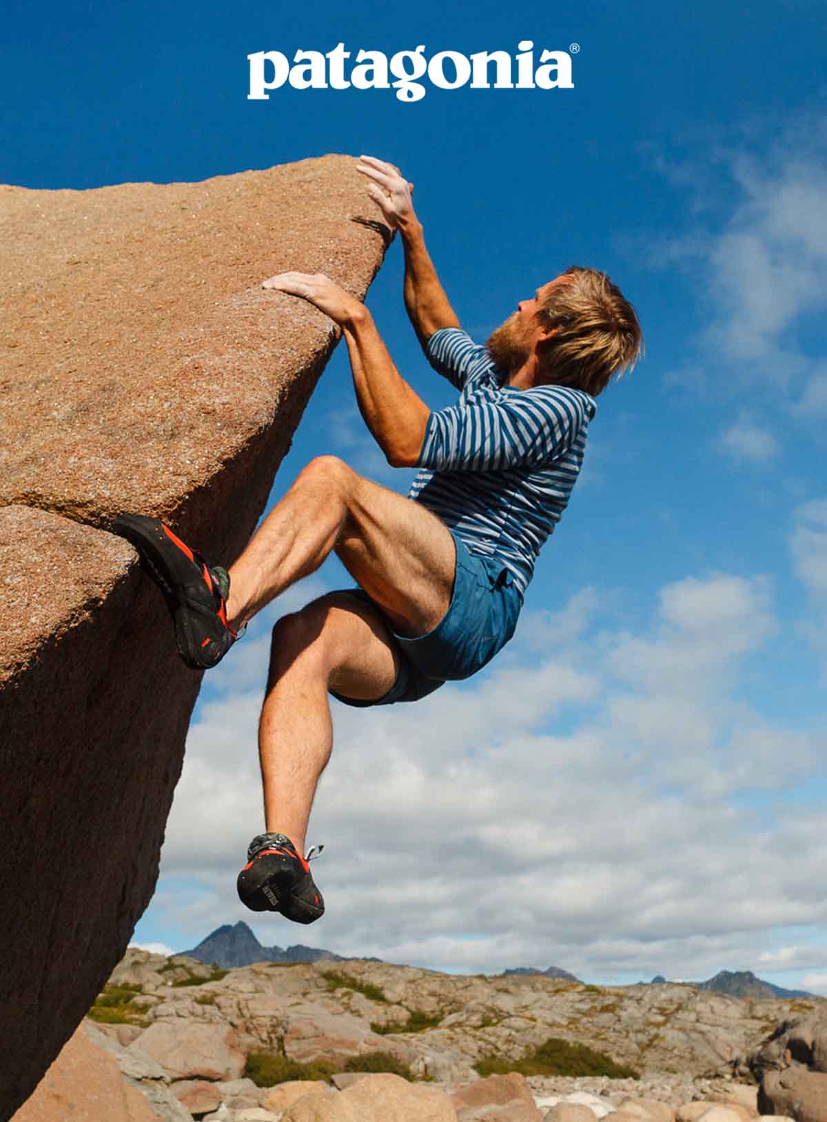 A person in shorts climbing a boulder.
