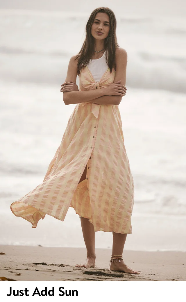 A woman wearing a checked button-front sundress over a tank top.