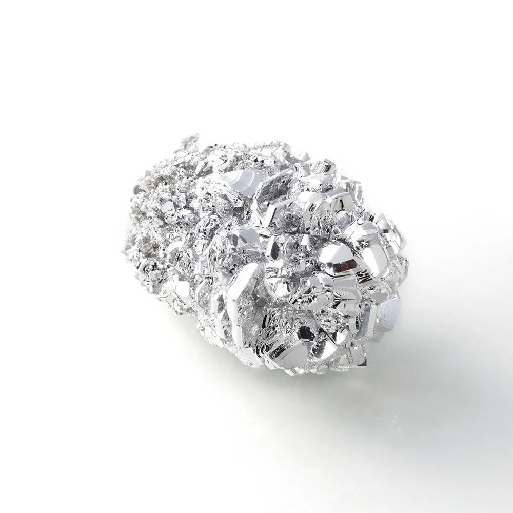 A sample of the earth metal Magnesium appears like a glossy, metal nugget.
