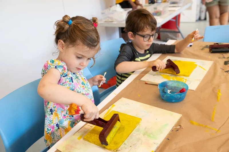 Children making prints with yellow paint