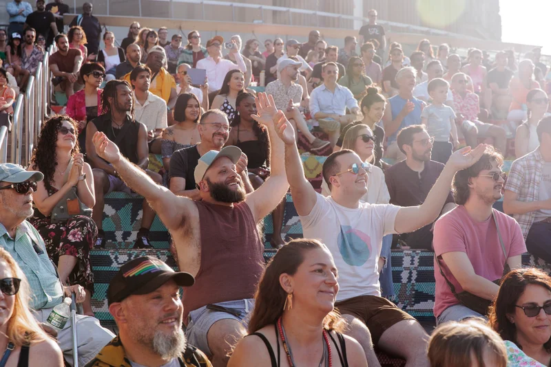 People seated on bleachers smiling and clapping