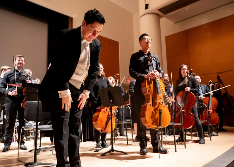 Musicians and a conductor taking a bow on stage