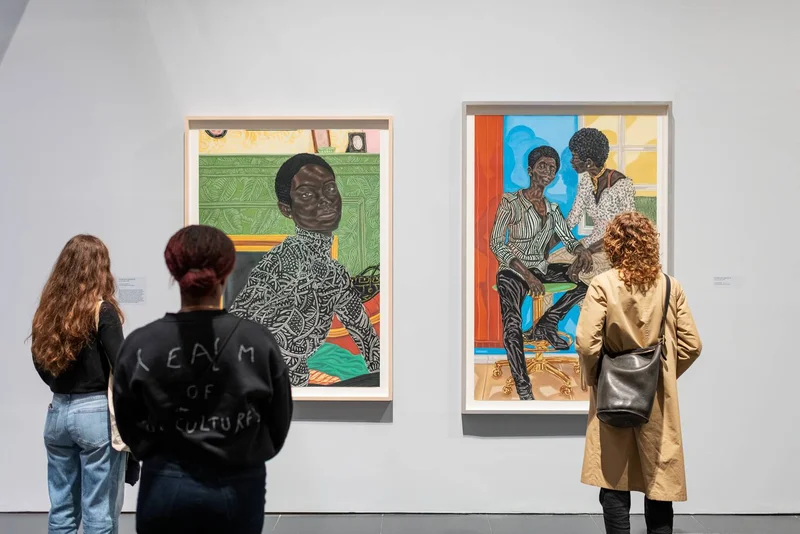 Three visitors standing in front of two artworks