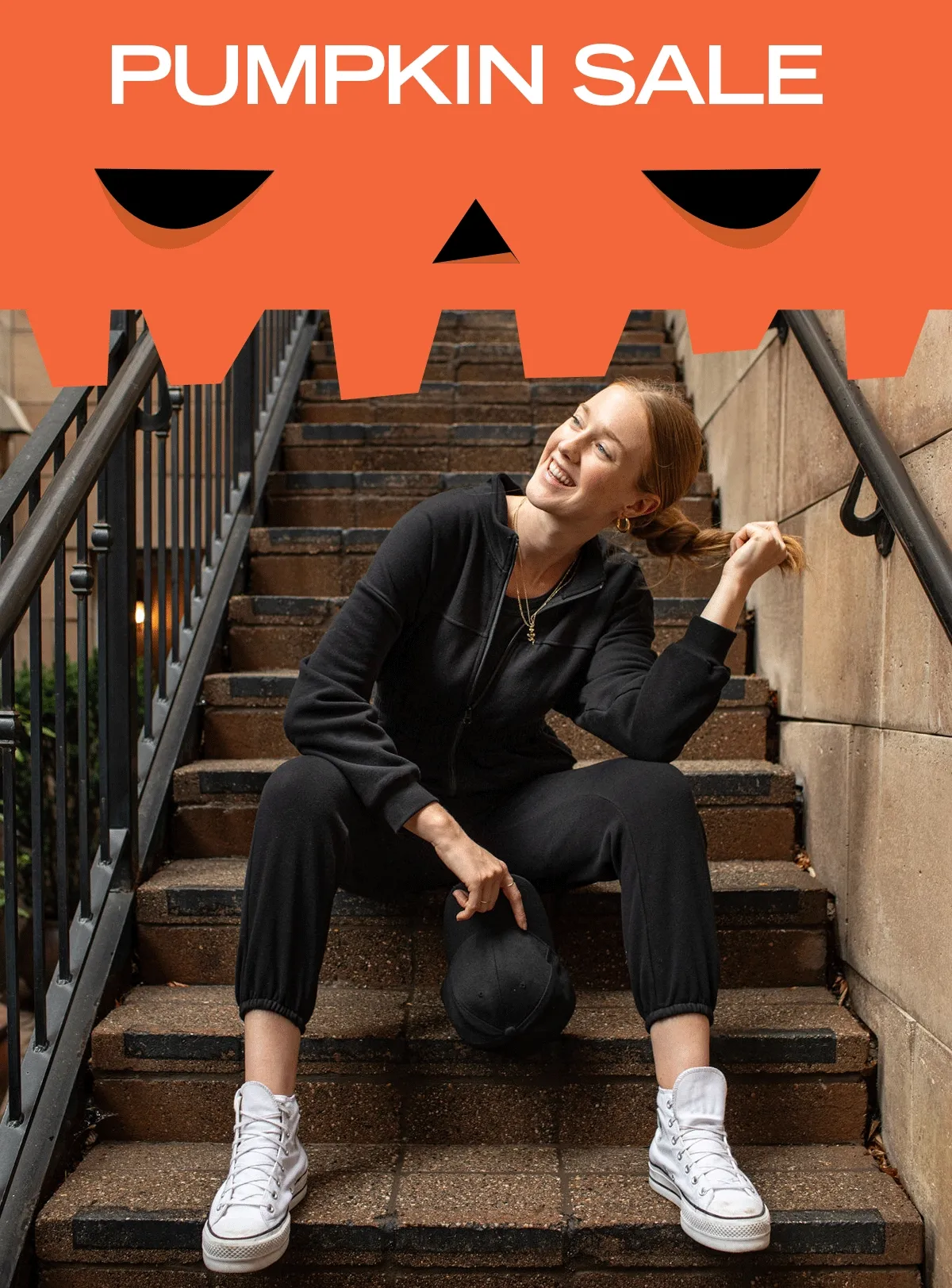woman sat on steps wearing black jumpsuit