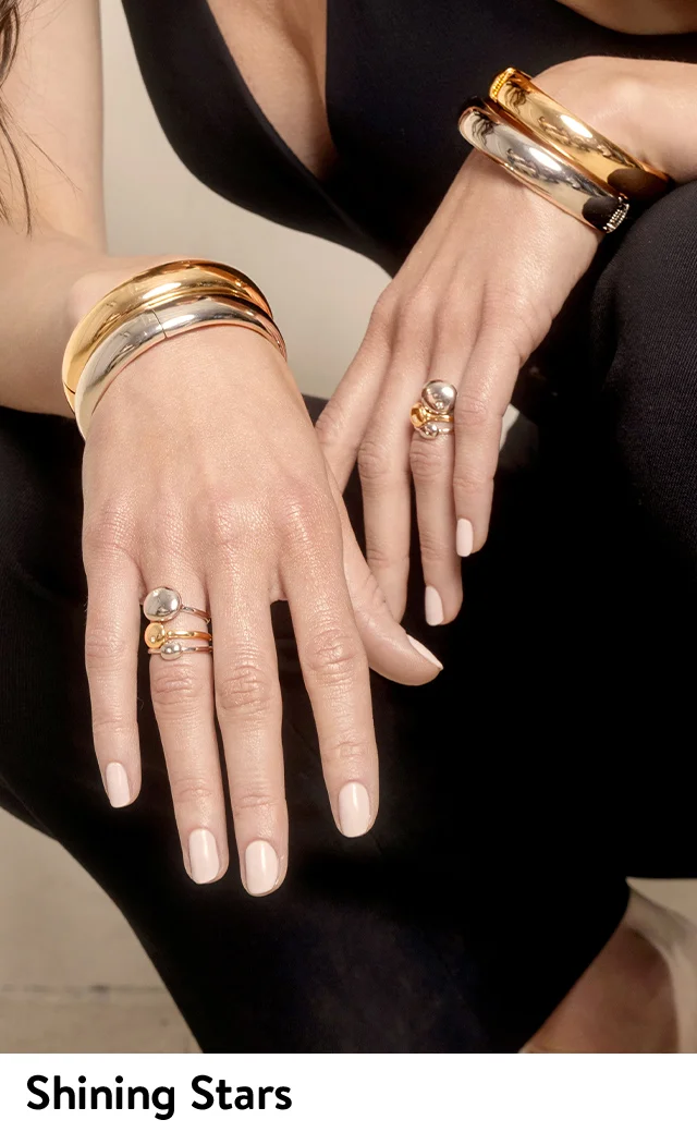 A woman wearing silver and gold bangles and rings.