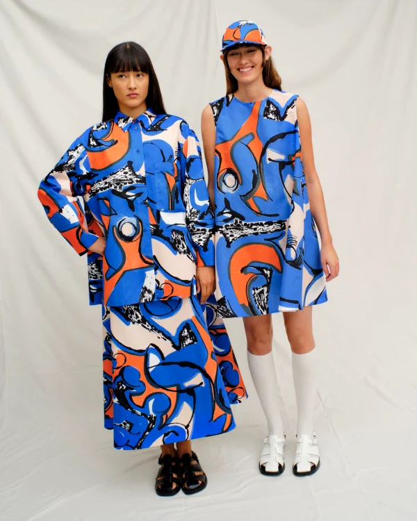 Two models posing side-by-side. One wearing the Kukkavera Eldfamn Cotton shirt styled with Puutarha Eldfamn Skirt. Other model is wearing the Anemonet Eldfamn Marimini dress.
