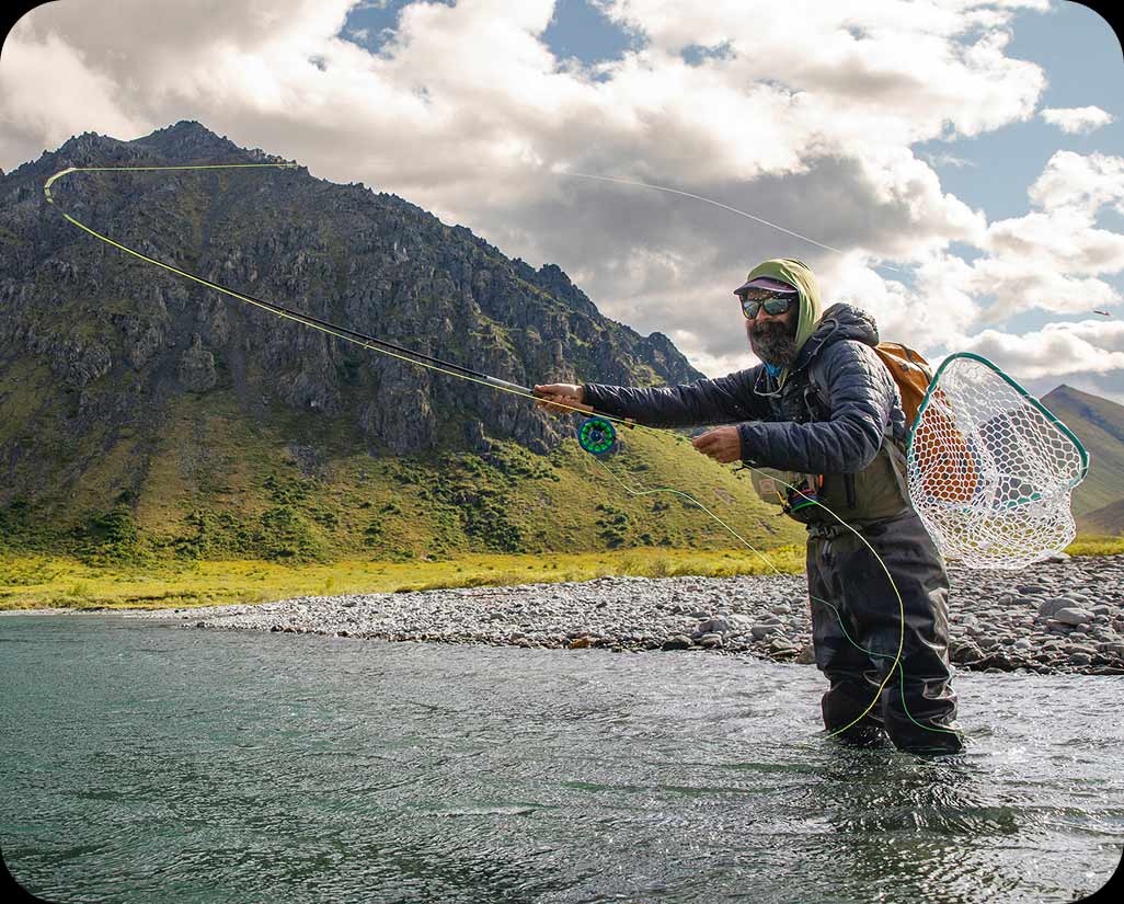 A person standing in a river fishing .
