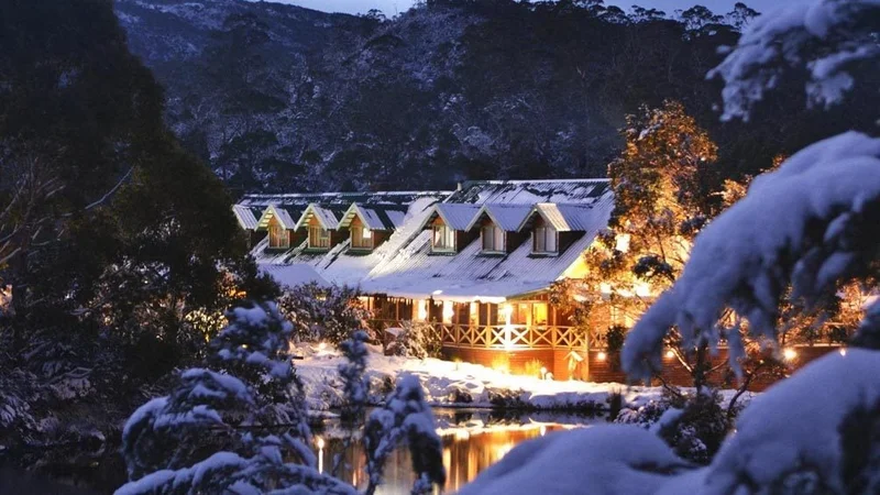 Image description: Snow covered exterior of Peppers Cradle Mountain Lodge at dusk in Tasmania.