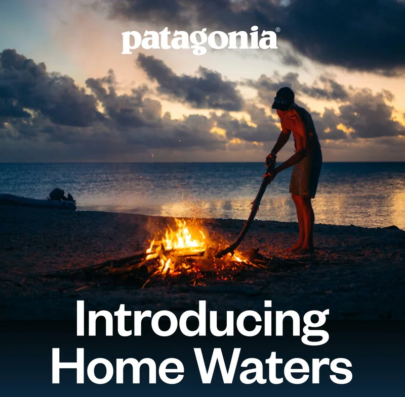 Patagonia. Introducing Home Waters. A person stokes a bonfire on a beach.