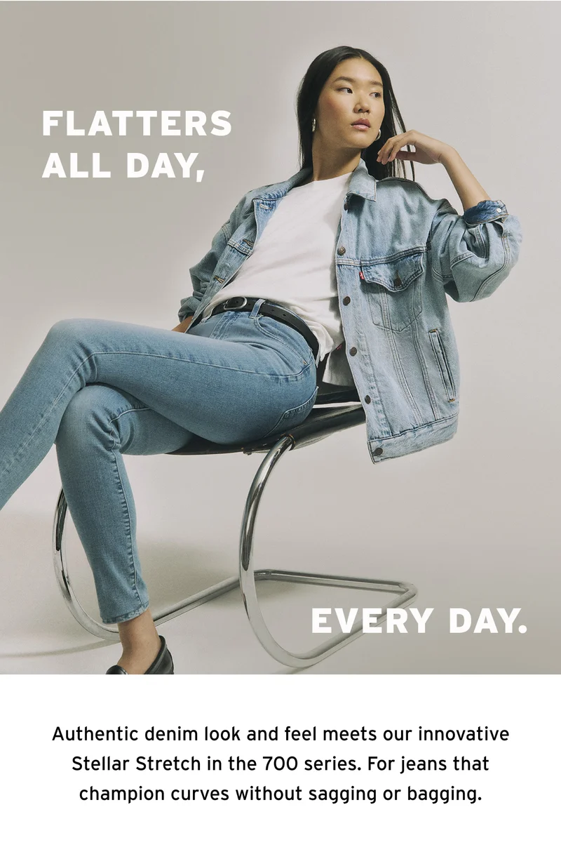 Woman sitting on a chair wearing a white tee and a light wash denim trucker jacket and jeans